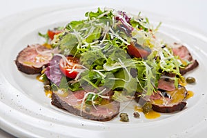 Rucola salad and beaf on a white plate