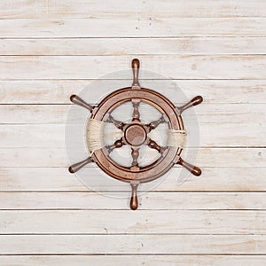 Rudder of sailing ship on wooden background