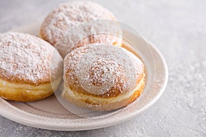 Ruddy delicious donuts berliners with filling sprinkled with powdered sugar on a white plate photo