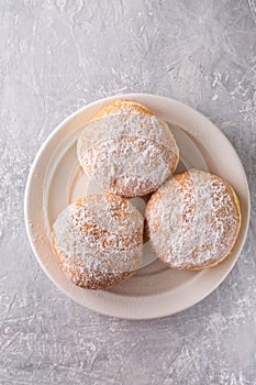 Ruddy delicious donuts berliners with filling sprinkled with powdered sugar on a white plate, top view photo