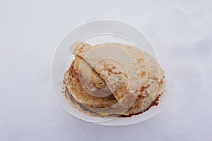 ruddy Russian pancakes on a plate in winter, pancakes on a plate outside