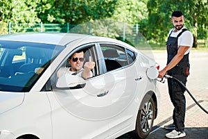 Rude driver showing middle finger to other car on gas station.