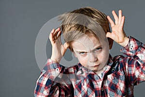 Rude kid playing with hands making face for determined attitude