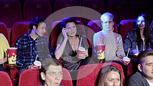 Rude woman talking on phone and disturbing other viewers in cinema.