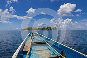 rudimentary blue boat in the middle of the sea in front of a small island with a blue sky photo