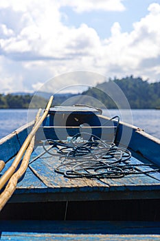 Rudimentary blue boat in the middle of the sea in front of a small island, travel concept photo