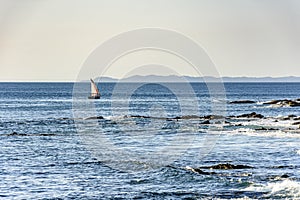 Rudimentary fishing boat sailing through the calm waters of Todos os Santos Bay photo
