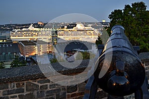 Rue de Remparts -Quebec - Canada - historical fortification cannon pointing to illuminated ship in port at evening