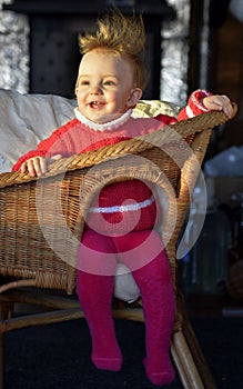 The ruffled hairdress. Portrait of the laughing little girl in a chair