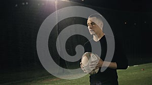 Rugby fan player in arena against rugby players training with ball, dark football arena