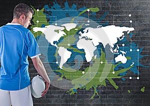 Rugby player holding ball next to Colorful Map with paint splatters on wall background