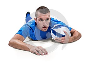 Rugby player looking away while lying in front with ball