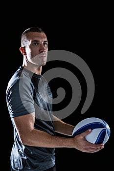 Rugby player looking way while holding ball