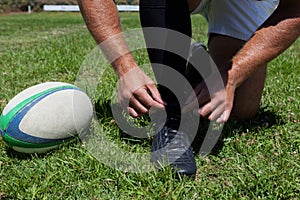 Rugby player tying shoes on field