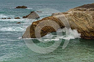 The rugged beauty of a rocky coastline meeting the vast expanse of the ocean under a dramatic sky, California