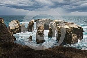 The rugged beauty of a rocky coastline meets the vast expanse of the ocean under a dramatic sky, California