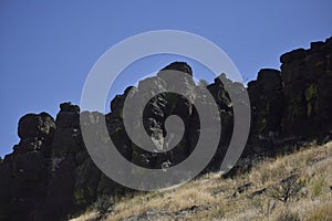 Rugged black Rock towering atop a high desert canyon wall photo