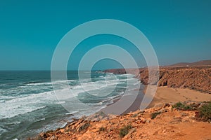 Rugged cliffside view of Aftas Beach and Atlantic Ocean in the chill coastal town of Mirleft, Morocco. photo
