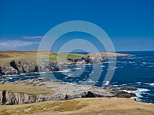 The rugged coastal cliff scenery and pristine turquoise waters around the island of Uyea in Northmavine, Shetland, UK.