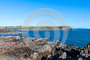 the rugged coastline around Whithorn, Dumfries and Galloway under clear blue skies