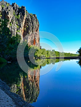 A rugged, eroded rocky outcrop reflected in a freshawater pool in Australia