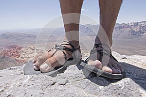 Rugged feet in primitive sandals on mountain photo