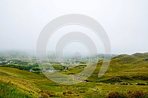 Rugged landscape at Malin Head, County Donegal, Ireland. Beach with cliffs, green rocky land with sheep on foggy cloudy