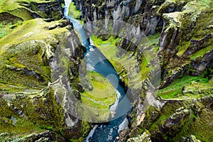 Rugged moss Fjadrargljufur canyon with Fjadra river flowing through in summer at Iceland