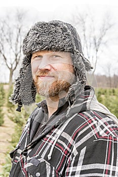 Rugged outdoorsman in fur hat and ear flaps, outside in winter,