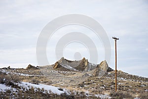 Rugged rock formation jutting out of sage brush covered hillside photo