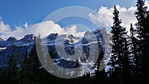 Rugged and snow-covered RÃ¤tikon mountains in the Alps in Montafon, Austria with the silhouettes of trees in fall.