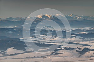 Snowy Little Fatra peaks and forest in mist at sunrise Slovakia