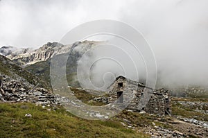 Ruin of old refuge in clouds. Monte Rosa massif near Punta Indren. Alagna Valsesia area, photo