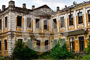 Ruined abandoned two-story house. Facade exterior of an old abandoned building with dirty bleached walls and broken