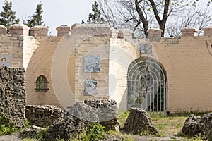 Ruined ancient architecture. Big stones and green grass. Gate in the background. Suuny