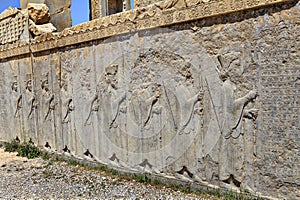 Ruined bas-relief with guards carved on wall of sandstone, Iran.