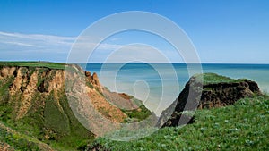 Ruined clay slope by the sea. Cracked clay cliff on the coast.