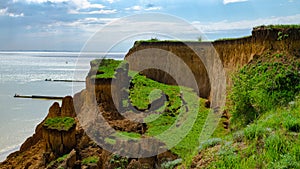 Ruined clay slope by the sea. Cracked clay cliff on the coast.