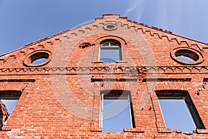 The ruined facade of an old abandoned red-brick building