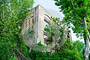 Ruined factory Abandoned house facade without roof with overgrown green vegetation