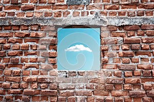 Ruined old brick wall window with sky and cloud view. Freedom, dream, imagination or isolation