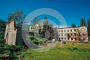 Ruined overgrown school in ghost mining town Akarmara, consequences of war in Abkhazia, green post-apocalyptic concept