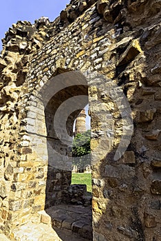 Ruined Quwwat ul-Islam Mosque with Qutb Minar tower in background at Qutub Minar complex