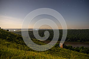 Ruined old castle tower at night on the river bank