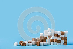 Ruined wall made of white and brown sugar cubes isolated on blue background
