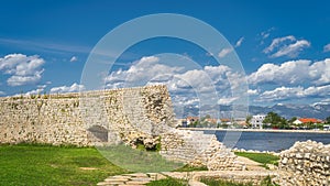 Ruined wall that was surrounding Nin village with view on modern district and Dinaric Alps