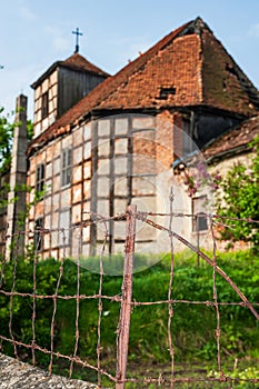 Ruins of the abandoned evangelical church made as half-timbered house with wood and red bricks. Blue sky and green grass and tree