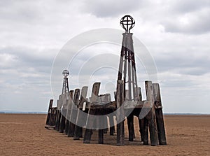 Ruins of the abandoned landing stage at saint annes pier in the ribble estuary lancashire at low tide with grey clouds