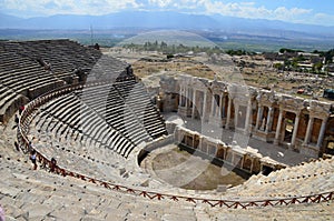 The ruins of the amphitheater of the ancient city of Hierapolis on the background of the mountains near Pamukkale, Turkey