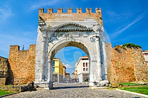 Ruins of ancient brick wall and stone gate Arch of Augustus Arco di Augusto and cobblestone road in old historical city Rimini